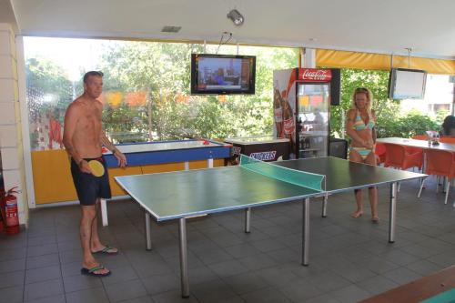 a man standing next to a ping pong table at Kavos Central in Kavos