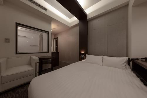 a bedroom with a large white bed and a chair at Furano Natulux Hotel in Furano