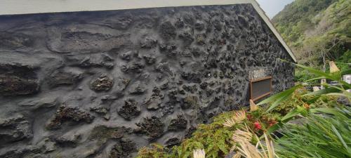 a rock wall with a window on the side of a building at Casas da Pedreira in Lajes do Pico
