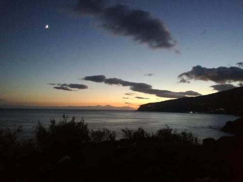 a sunset over a body of water with the moon at Casas da Pedreira in Lajes do Pico