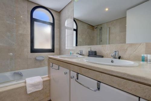 een badkamer met 2 wastafels, een bad en een spiegel bij 4 Bedroom Townhouse 200 meters from the Beach! in Estepona
