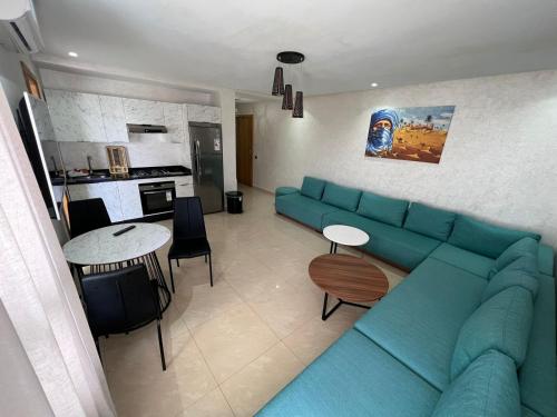 a living room with a blue couch and a kitchen at CASA BEACH HOTEL in Sidi Rahal