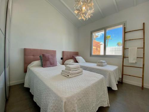 1 dormitorio con 2 camas con sábanas blancas y ventana en Sun golf house en Maspalomas