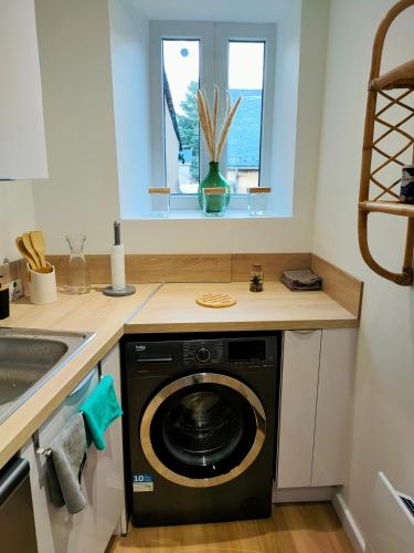 une cuisine avec une machine à laver sous un comptoir dans l'établissement Superbe T2 Aux Pieds des Cimes, lumineux, calme, classé 4 étoiles, à Bagnères-de-Bigorre