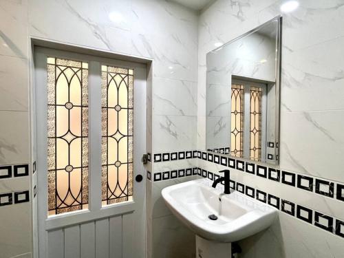 a white bathroom with a sink and a mirror at DiscoveryHome2 at Pratunammarket in Bangkok