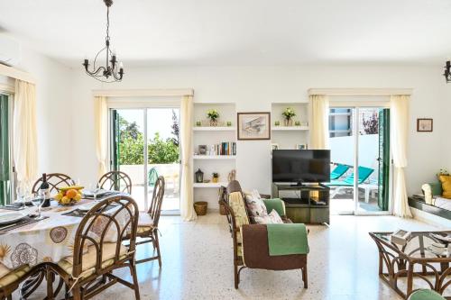 a living room with a table and chairs and a television at Villa 361-Walk to Protaras Fig Tree Bay & Amenities in Protaras