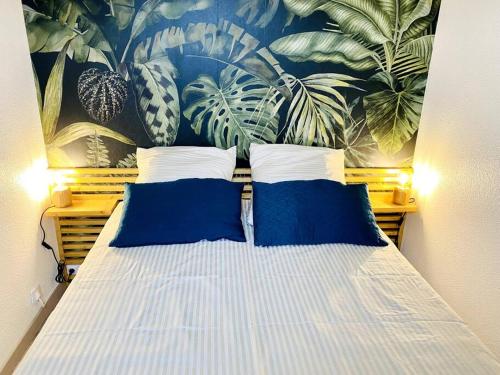 Bel appartement en bord de mer avec piscine في لاكانو-أوسيان: سرير مع وسائد زرقاء وبيضاء في غرفة النوم