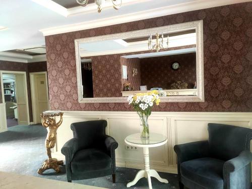 sala de estar con 2 sillas y mesa con espejo en Savoy Hotel en Chişinău