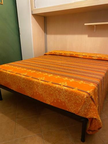 a bed in a room with an orange blanket on it at One Love Ortigia in Syracuse
