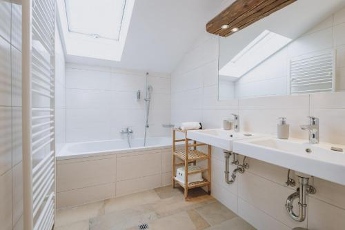 a white bathroom with two sinks and a bath tub at Chalet Badia by we rent, SUMMERCARD INCLUDED in Zell am See
