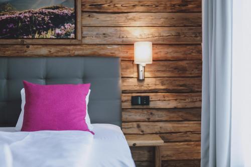 a bedroom with a pink pillow and a wooden wall at Chalet Badia by we rent, SUMMERCARD INCLUDED in Zell am See