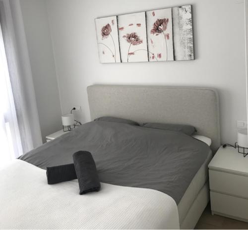 a bedroom with a bed with a gray blanket and flowers at 49 Laguna Beach in Torrevieja