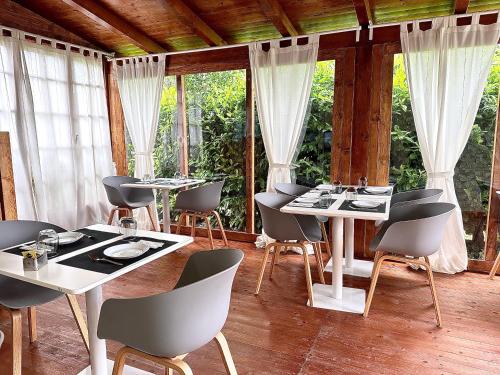 Un comedor con mesas y sillas y ventanas. en Abitatt, en Fosdinovo