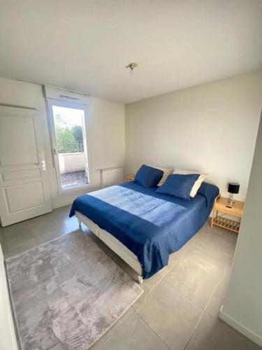 Un dormitorio con una cama con sábanas azules y una ventana. en Appartement cosy proche Bordeaux, en Cenon