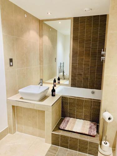 a bathroom with a sink and a tub and a mirror at Victoria Rooms in Manchester