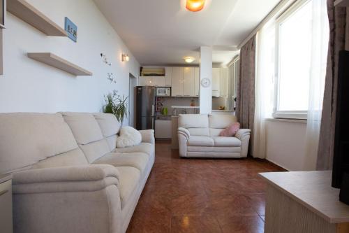 a living room with two white couches and a kitchen at Lanterna Puntamika apt. near beach in Zadar