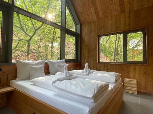 a bedroom with two white pillows on a bed with windows at Baumwipfelhaus in Annweiler am Trifels