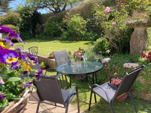 una mesa y sillas en un jardín con flores en Spacious flat St Ives former farmhouse, parking en St Ives