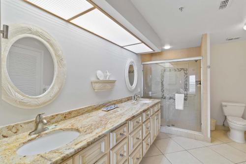 ein Badezimmer mit Waschbecken, Toilette und Spiegel in der Unterkunft Luxury Direct Beachfront Views - Crimson #201 in St Pete Beach