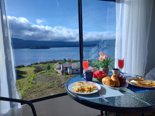 einen Tisch mit Teller mit Lebensmitteln und Blick auf das Wasser in der Unterkunft Cabañas Villas Del Lago in Cuítiva