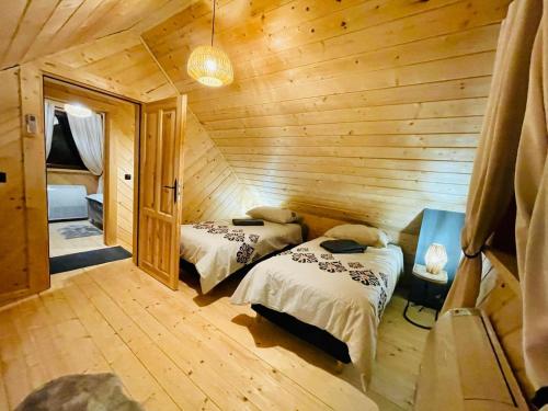 a bedroom with two beds in a wooden cabin at Osada Foltynówka in Sablówka