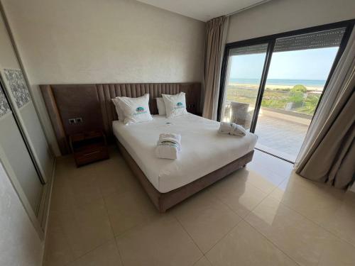 a bedroom with a bed with a view of the ocean at CASA BEACH HOTEL in Sidi Rahal
