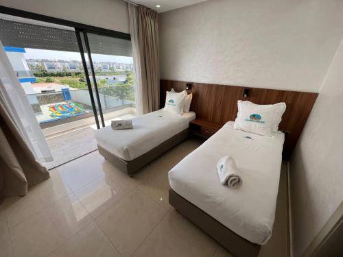 a hotel room with two beds and a large window at CASA BEACH HOTEL in Sidi Rahal