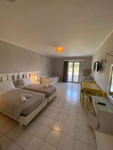 a bedroom with two beds and a sink and a desk at Irina Beach Hotel in Tigaki