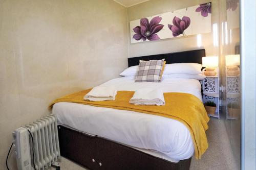 1 dormitorio con 1 cama grande con manta amarilla en Ocean View 8 - 1 Bedroom Chalet - Llanrhidian, en Llanrhidian
