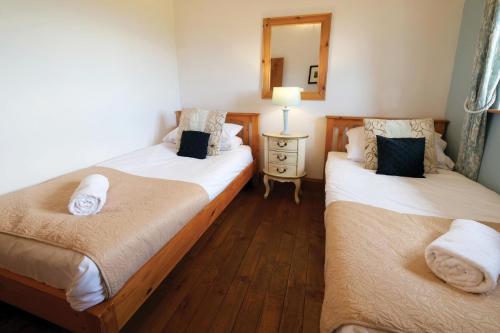 two twin beds in a room with a mirror at Ocean View Cottage 2 - 2 Bed Cottage - Llanrhidian in Llanrhidian
