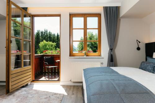 a bedroom with a bed and a balcony with a table at MONDI Hotel am Grundlsee in Grundlsee