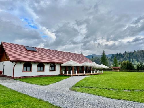 a building with a red roof on a grass field at Biotour Camping & Restaurant in Ghimeş