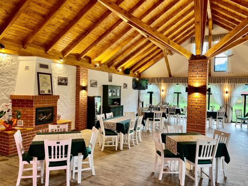 jadalnia ze stołami i krzesłami oraz kominkiem w obiekcie Biotour Camping & Restaurant w mieście Ghimeş