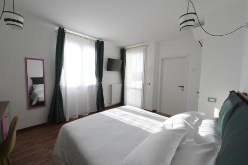 a bedroom with a white bed and two windows at TerrazzaPonente in Monte San Pietro