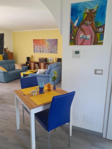 a living room with a table and blue chairs at TerrazzaPonente in Monte San Pietro