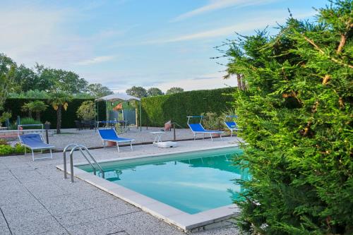 a swimming pool with blue chairs next to a hedge at Agriturismo Da Rosy in Codevigo
