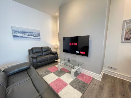 a living room with a couch and a flat screen tv at Jacksons Apartment, Close to Tynemouth in Tynemouth