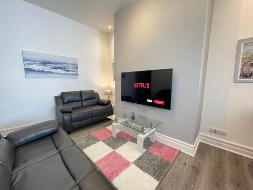 a living room with a couch and a flat screen tv at Jacksons Modern Retreat Close to Tynemouth in Tynemouth