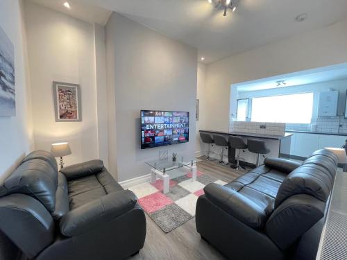 a living room with black leather furniture and a flat screen tv at Jacksons Apartment, Close to Tynemouth in Tynemouth