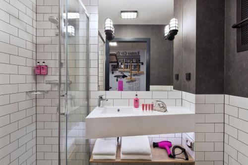 La salle de bains est pourvue d'un lavabo et d'une douche. dans l'établissement Moxy Katowice Airport, à Pyrzowice