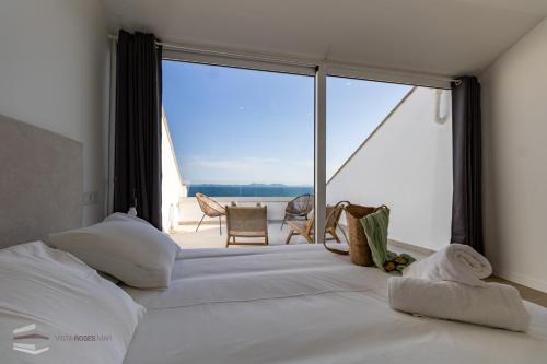 a bedroom with a large white bed and a large window at Vista Roses Mar - El Brancs in Roses