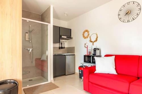 a living room with a red couch and a shower at Studio neuf avec acces piscine in Valergues