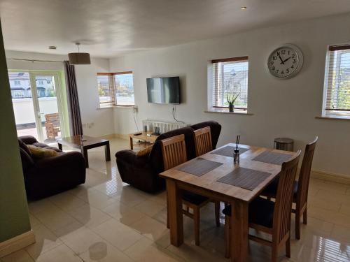 een woonkamer met een tafel en een klok aan de muur bij Luxury apartment hawthorns in Sligo