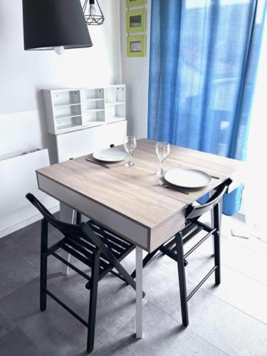 una mesa de madera con 2 copas de vino y 2 sillas en Magnifique appartement avec terrasse Roof-Top, en Saint-Étienne