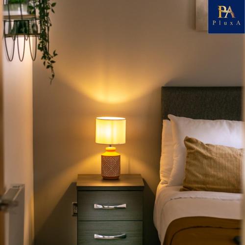 a lamp on a night stand next to a bed at Pluxa The Hideaway - Fully private serviced apartment & parking in Birmingham