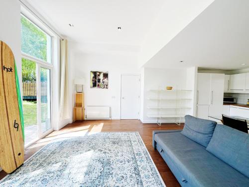 a living room with a blue couch and a large window at Portobello Dock - Canal Views with Garden in London
