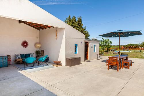 eine Terrasse mit einem Tisch, Stühlen und einem Sonnenschirm in der Unterkunft Bloomoon House in Bunheiro