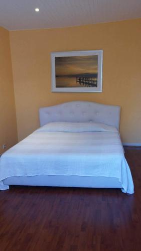 1 cama blanca en un dormitorio con una foto en la pared en Duxplex aux Portes Monaco, en Beausoleil