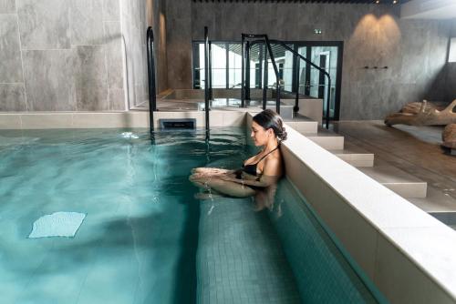 a woman sitting in the water in a swimming pool at Hôtel Roz Marine Thalasso Resort in Perros-Guirec