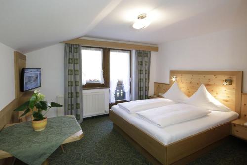 a bedroom with a large white bed and a window at Pension Wendlhof in Obergurgl